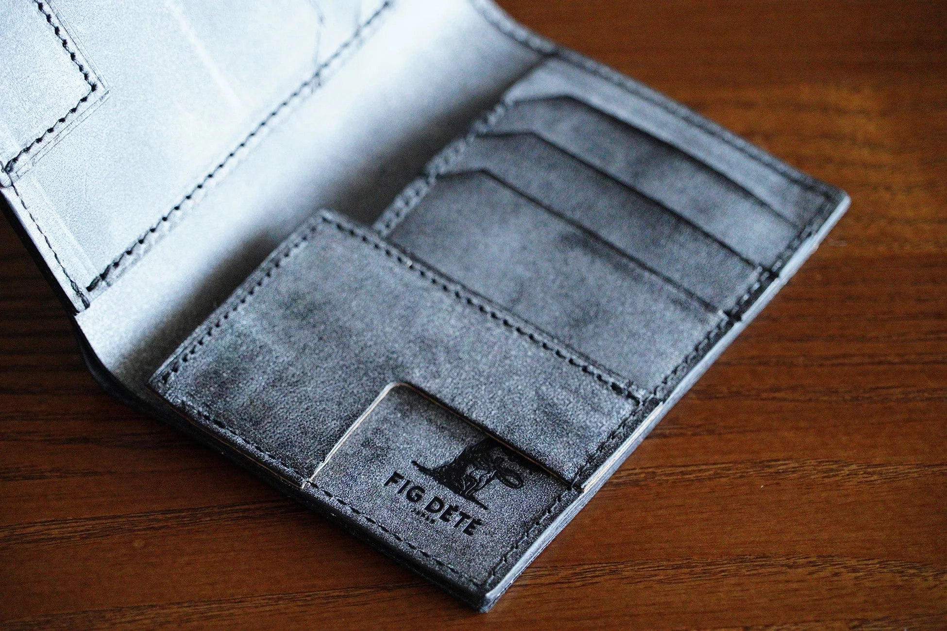 木製のテーブルに置かれたダークグレーの革製カードケース