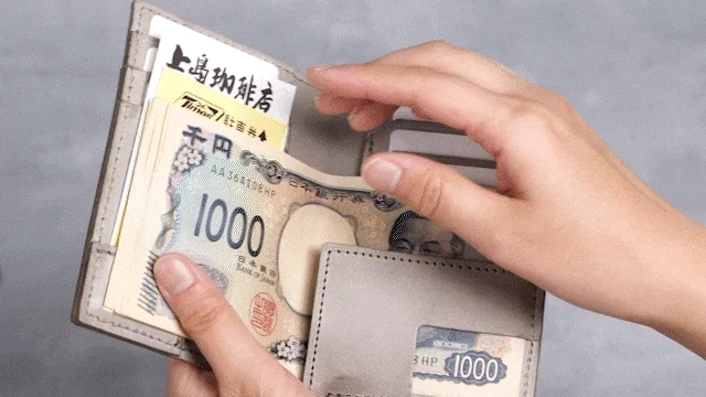 灰色の財布から日本の千円札の束を取り出している様子