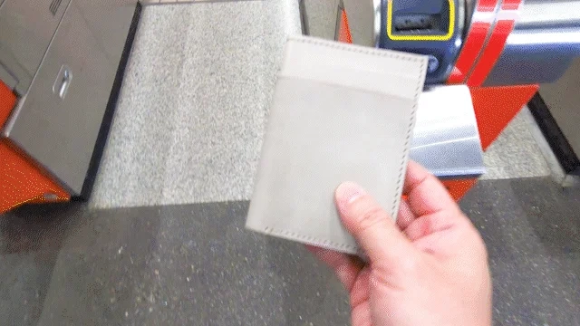 人物が駅の自動改札機にパスケースをかざして通過しようとしている様子